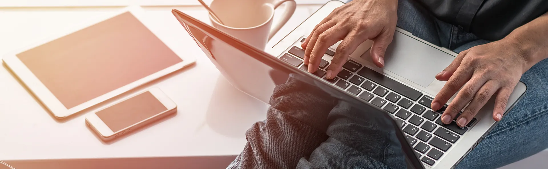 Image of person typing blog update with coffee on desk