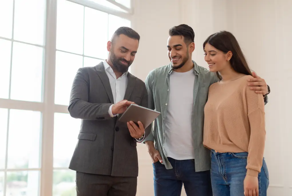 A young couple grin and digitally sign their First Home Loan documents with a broker.