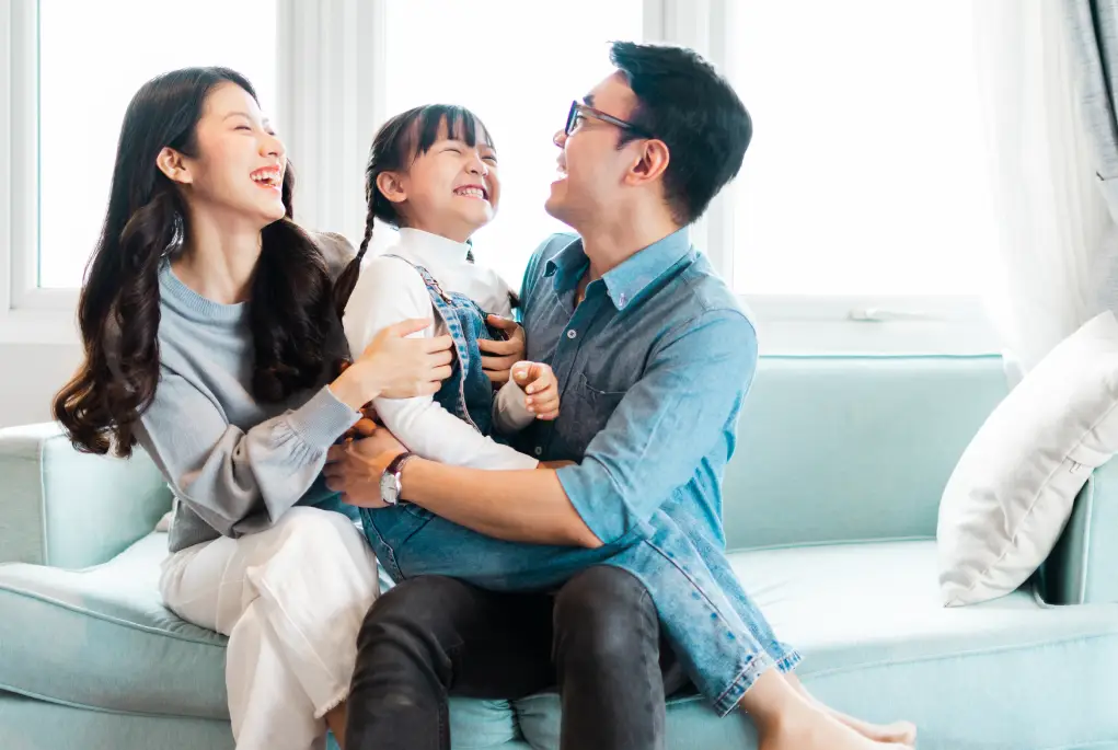 Two young doctor parents laughing with their daughter.