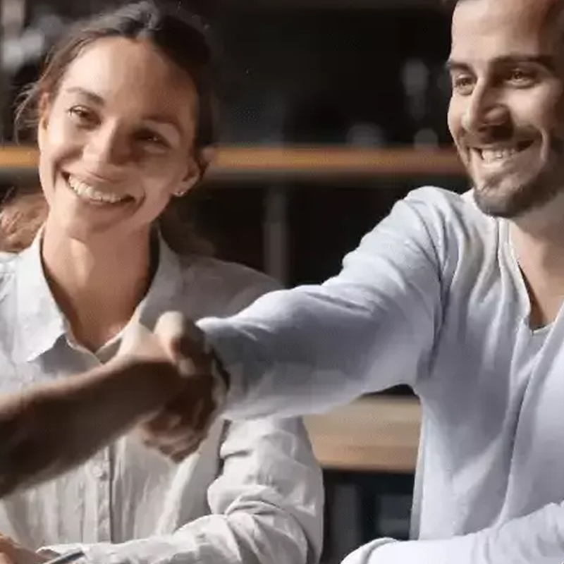 A couple shaking hands with their broker after making Home Loan repayment calculations.