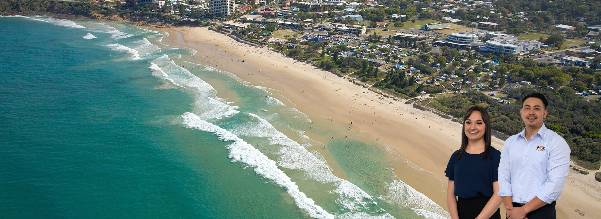Antonio and Paige standing in the foreground of a popular SUnshine Coast beach.