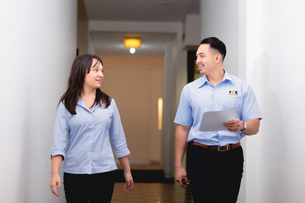 Antonio and Paige walking down the corridor discussing commercial property loan options. 