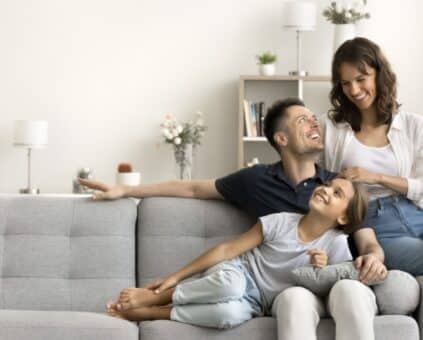 Happy family sitting on the couch after discovering the ways to pay of their mortgage quicker
