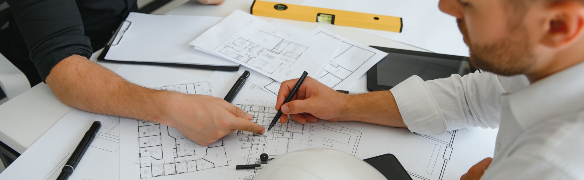 Two people reviewing architectural blueprints and floor plans for a construction home loan project