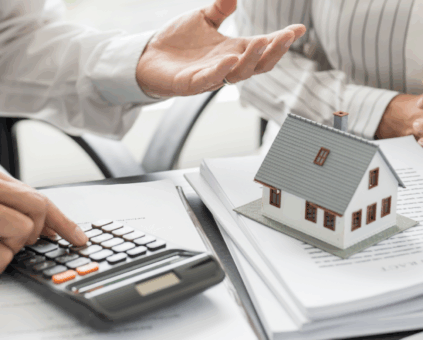 Lending Specialist calculating investment property costs with house model and loan documents for rentvesting