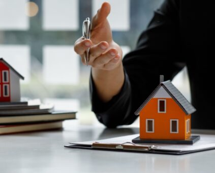 Mortgage broker with an orange model house in front of them discussing bad credit home loans