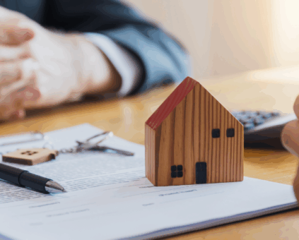 Wooden house model on loan documents with piggy bank and calculator, representing home loan planning and mortgage financing