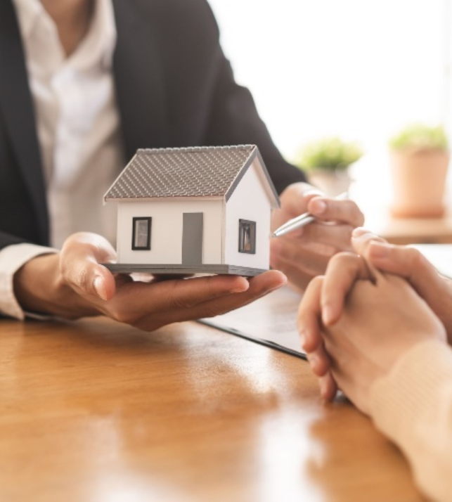 Mortgage broker presenting house model to self-employed borrower during home loan assessment