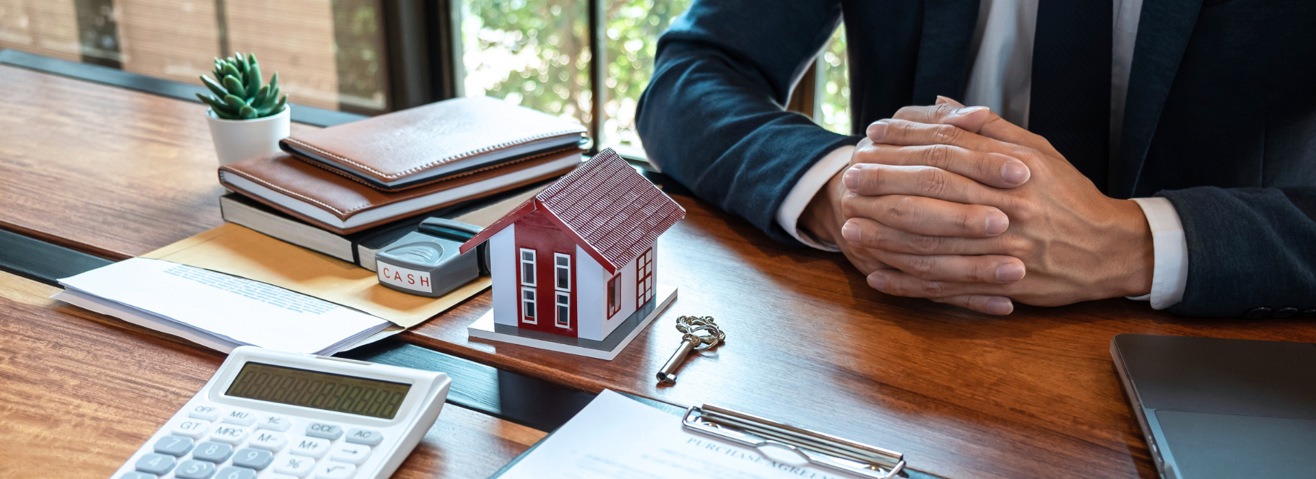 Mortgage broker with calculator, house model, and keys on desk during a home loan consultation and mortgage application review
