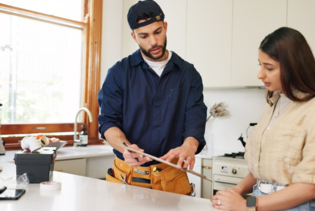 Self-employed tradesperson at work in a clients kitchen going over the work completed