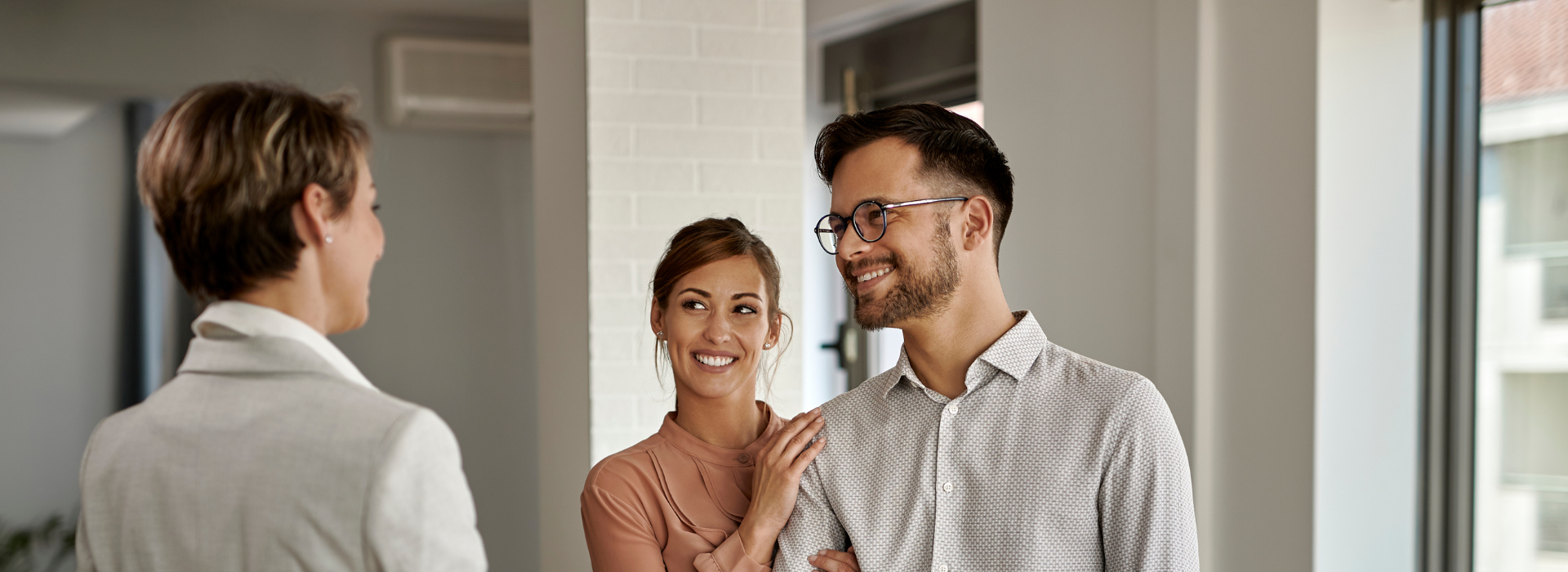 Couple shaking hands with loan officer while viewing an investment property