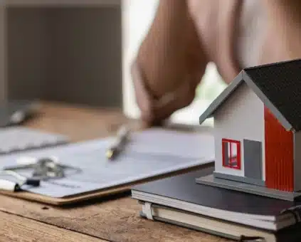 Miniature house on notebook with loan paperwork, representing self-employed home loan application process