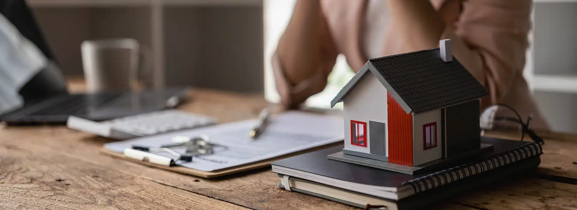 Miniature house on notebook with loan paperwork, representing self-employed home loan application process