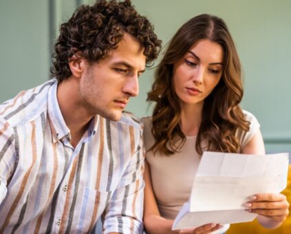 Coast couple reviewing their home loan statement at a kitchen table with a Fox Home Loans broker